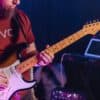 Man with red shirt playing guitar.