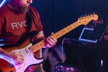 Man with red shirt playing guitar.