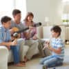 Portrait of siblings and their father playing musical instruments and their mom watching, happily. They are playing guitar, flute and a maracas, which is also called a musical shaker.