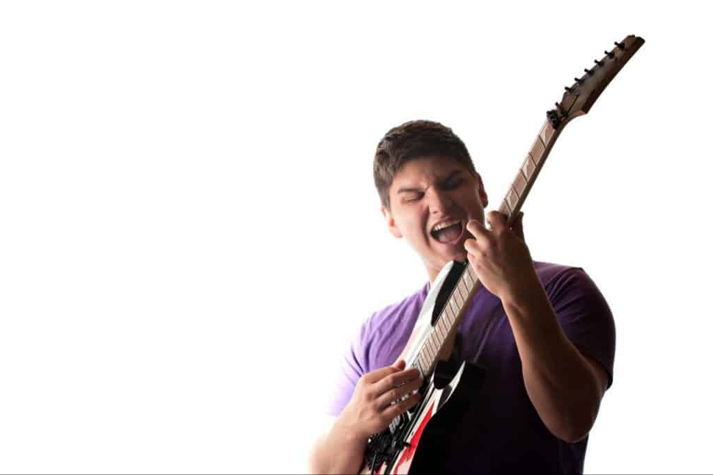 Teen playing guitar aggressive, having fun.