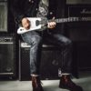 Man in jeans playing guitar on top of amplifier