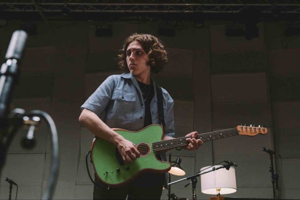 Young man playing green toned guitar, having fun.