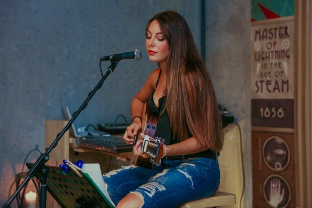 Woman playing guitar on chair.