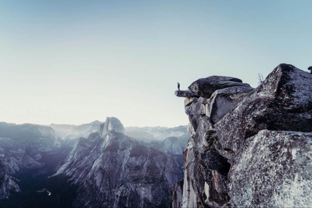 Man standing on the edge on real high cliff, on gigantic mountain.