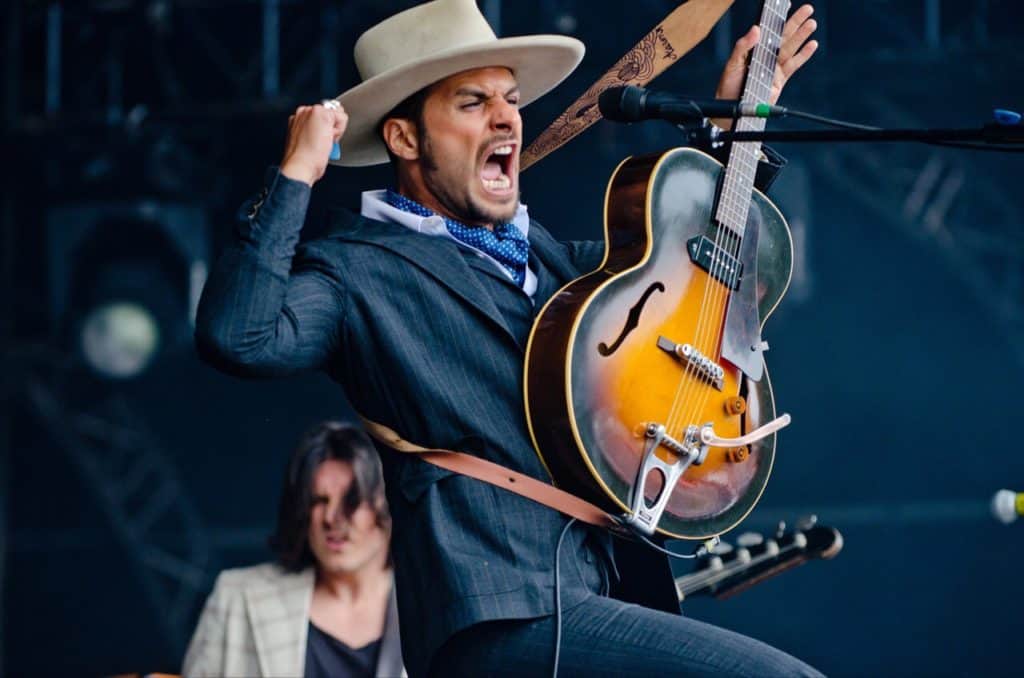 Man real excited holding guitar and one fist in the air.