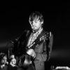 Man playing guitar on stage confidently. Black and white picture.