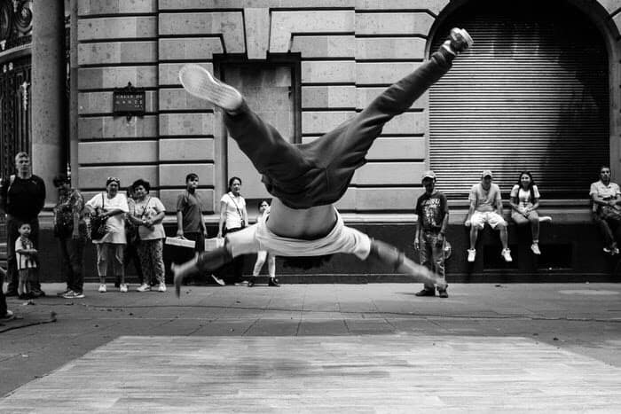 Man dancing and jumping outside, in front of crowd.