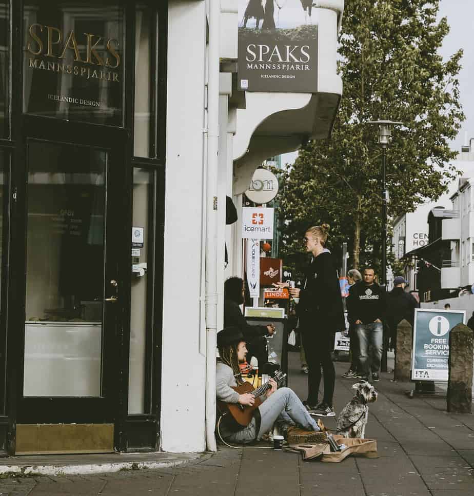 Outside busking, playing guitar outside a shop, having fun.