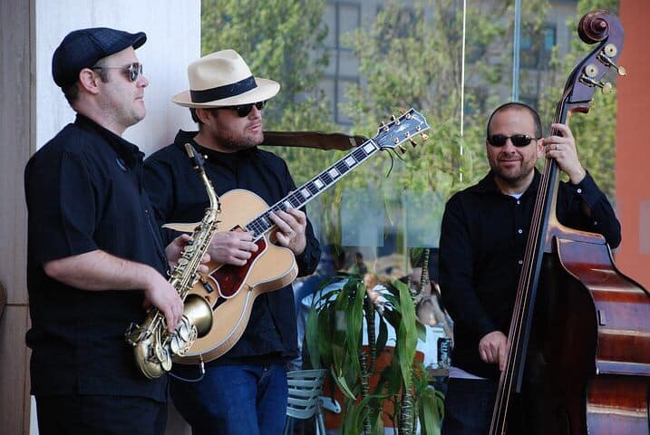 Guitar player with saxophone and vintage bass players, outside playing, enjoying the sun.