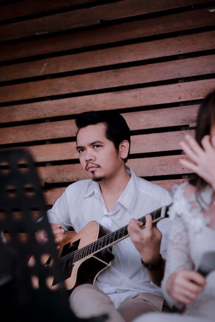 Man playing guitar sitting down.