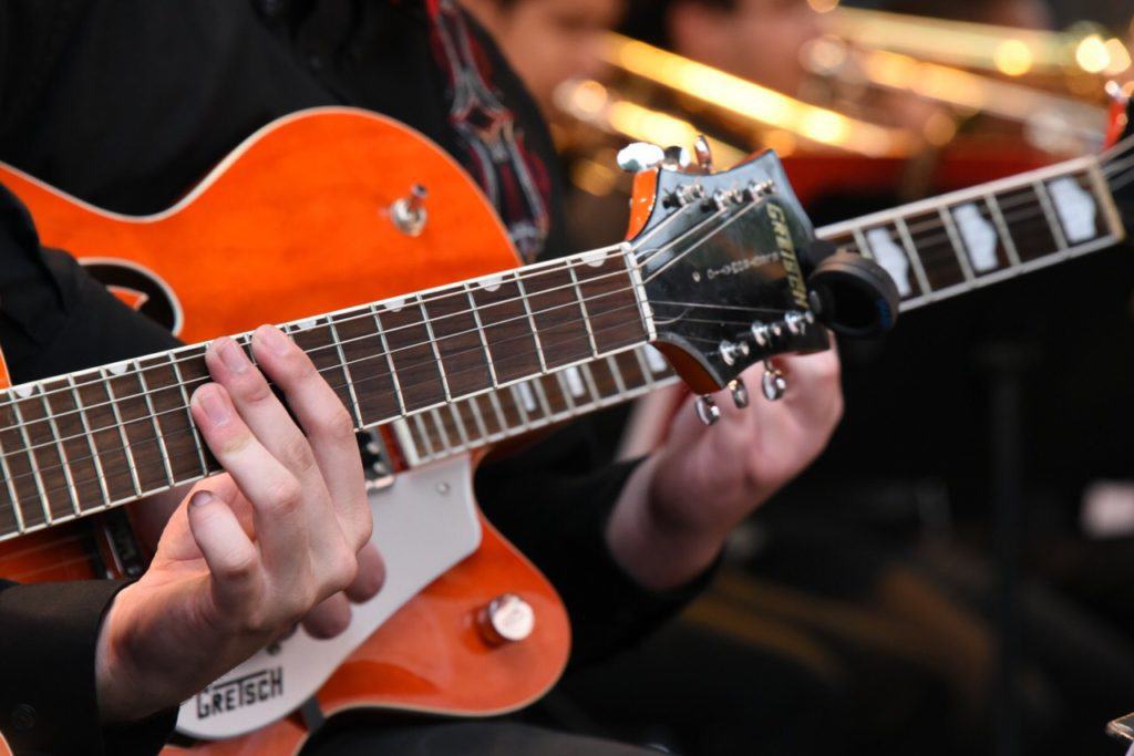 Playing guitar with another guitar player, side by side.