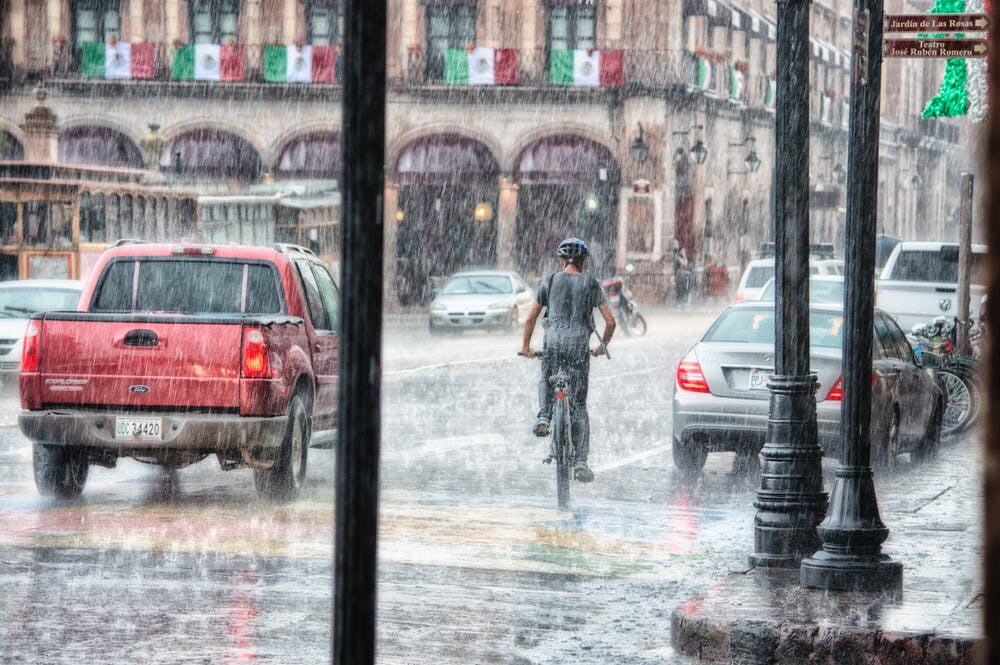 Rainy weather, as vehicles drive through it. As well as a bicyclist.