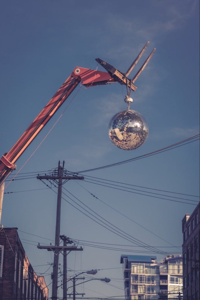 Disco ball on demolition truck ball crane, real high in the air.