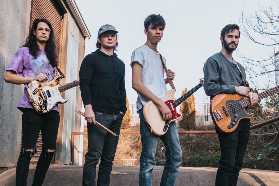 Guitar band pose for photo shoot on a nice day outside. Also have their instruments.