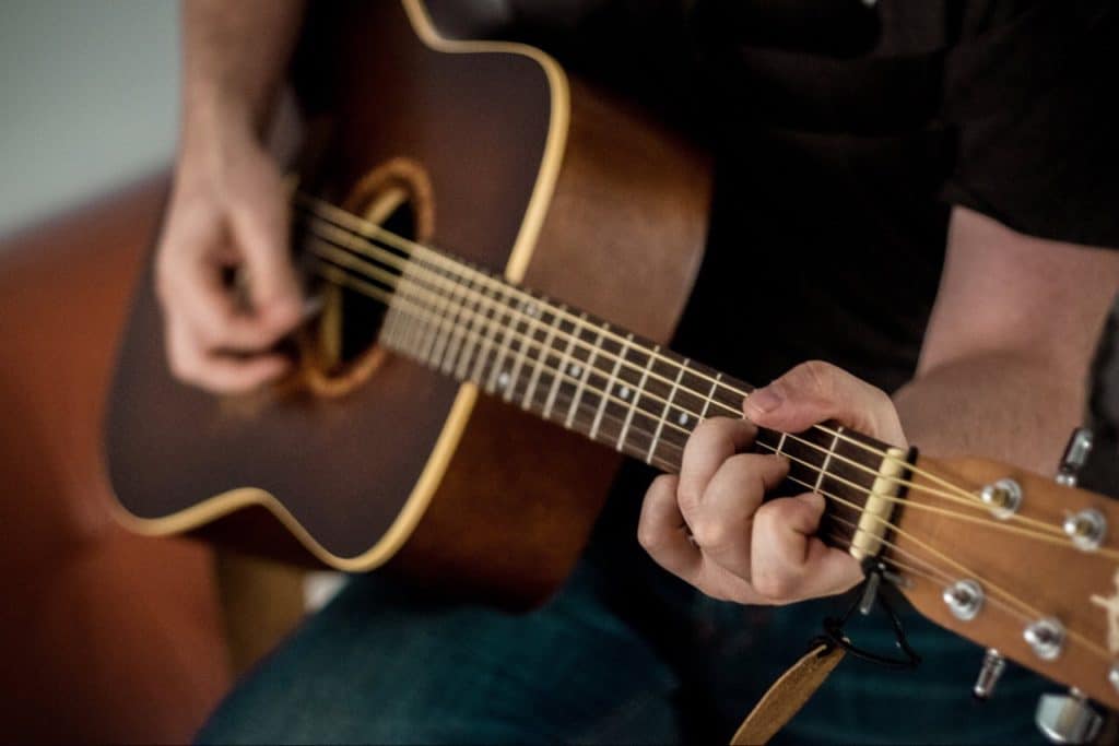 Man playing brown acoustic guitar.