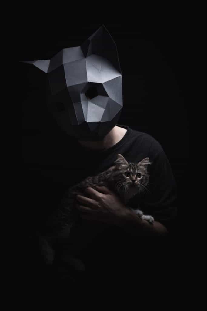 Metal cat face mask with cat in his hand.