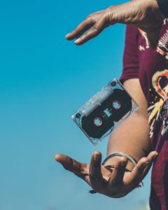 Man tosses cassette tape in the air between his two hands. Image from pixels.com