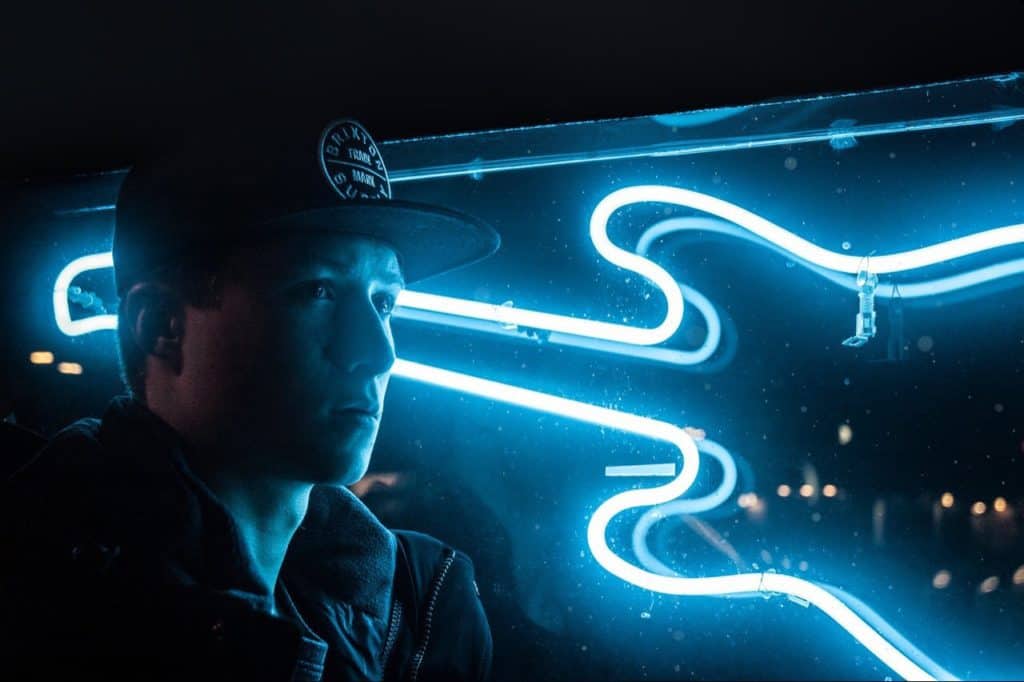 Man with lighted guitar sign behind him.