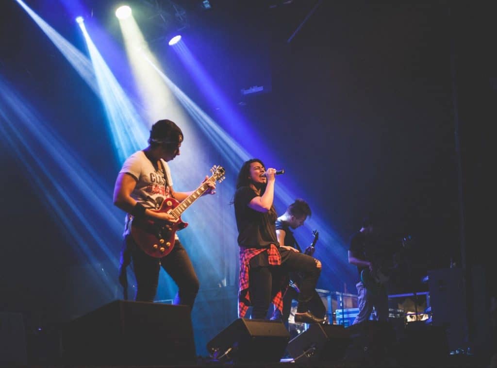 Man and woman playing guitar on stage with blue lights shining down on them, having fun!