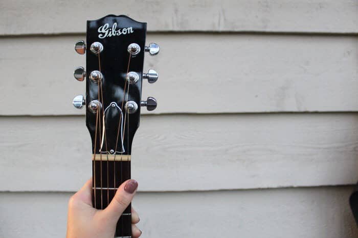 Girl holding Gibson guitar in her hands.