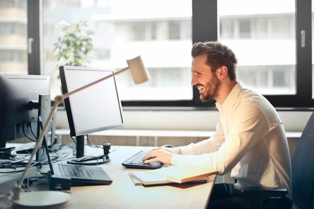 Man smiling looking at computer screen.