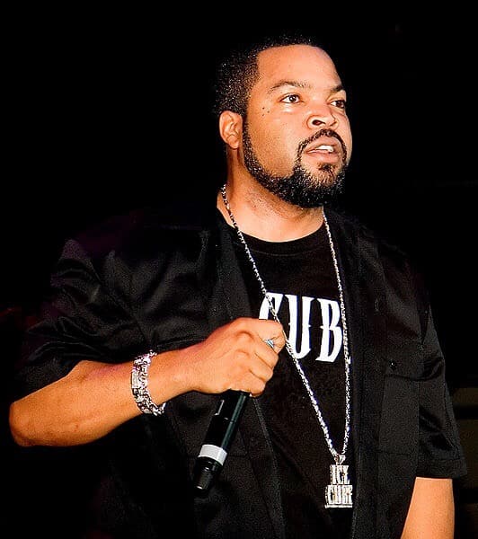 Ice Cube with microphone. And he has a chain necklace with Ice Cube written on it and also T-shirt. Photo courtesy of Philip Litevsky at commons.m.wikimedia.org Philip Litevsky is from Toronto Canada.