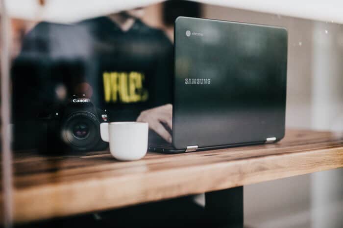 Man looking at laptop computer on desk and drinking coffee.