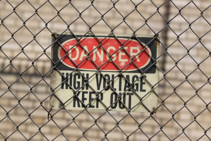 Danger, High Voltage, Keep Out, sign, hanging on a chain link fence.