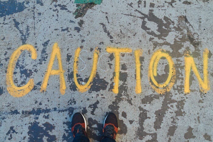 Caution spray painted on sidewalk.