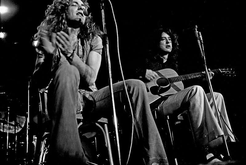 Jimmy Page and Robert Plant of Led Zeppelin playing guitar and clapping and singing.