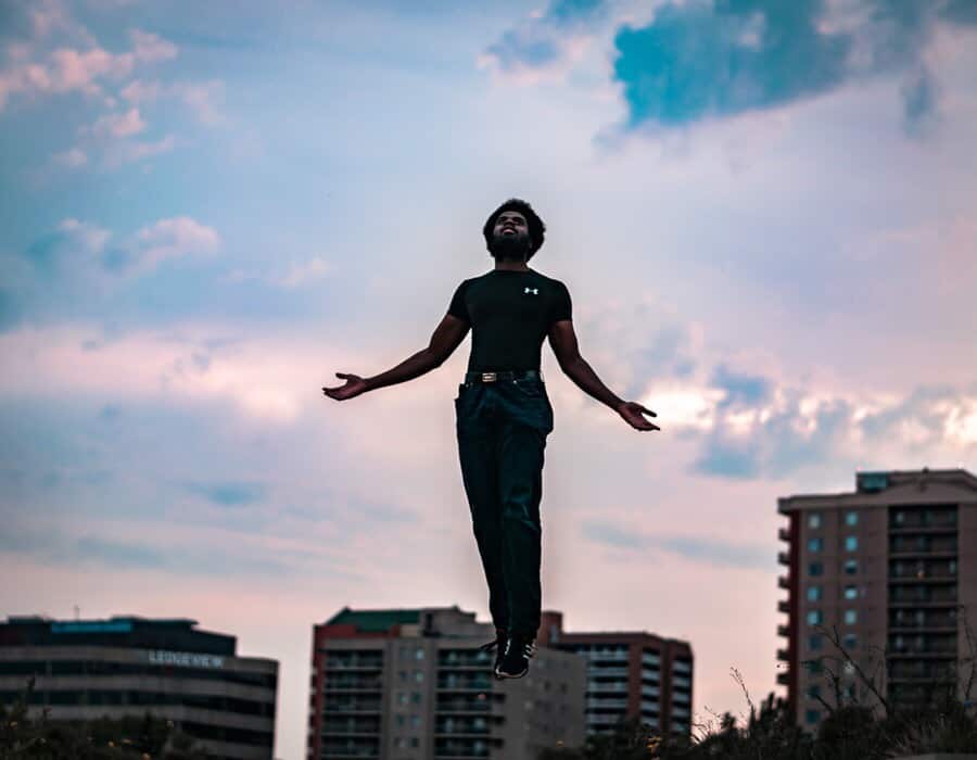 Man being lifted up off his feet toward the height of the buildings surrounding him.