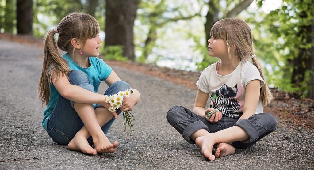 Young kids talking to each other, sitting down.