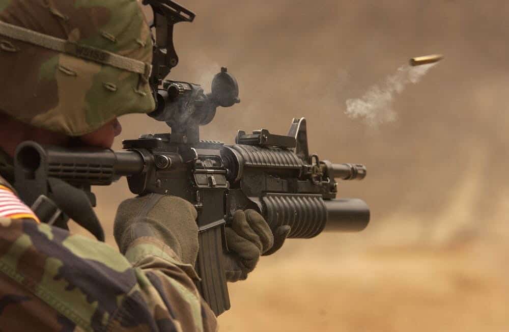 Soldier shooting rifle with bullet shown coming out of it because picture was taken at the right time.