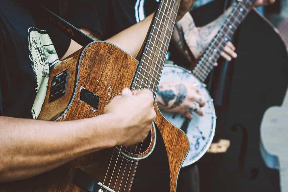 Man strumming guitar with banjo player.