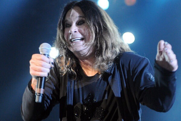 Ozzy Osbourne smiling and holding microphone in concert, with lights shining behind him @ Arena Anhembi. Photo courtesy of Focka from flickr.com