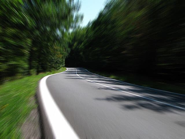 Street moving a very fast speed, by vehicle. Vehicle windshield camera, point of view, outside.