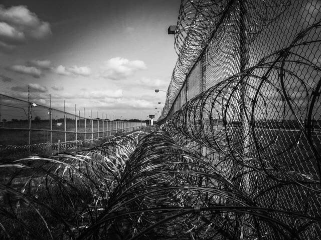 Prison fence with HUGE barbed wire on it. Black and white picture.