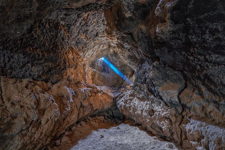 Boulder underground, with blue light beam, shining down in it.