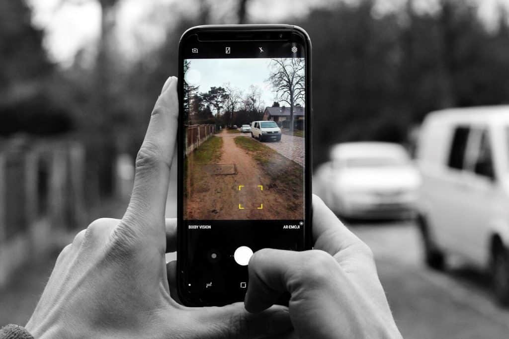 Person filming side of the road and cars.