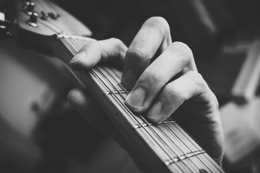 Man playing F barre chord on the guitar. Black and white picture.