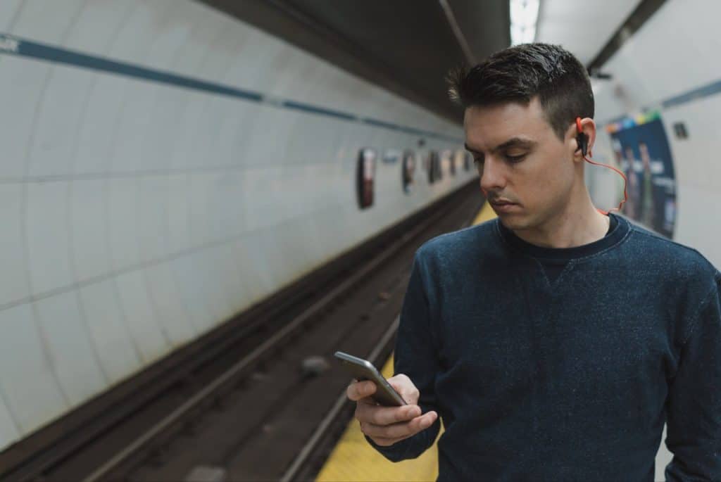 Young man looking at cellphone inside a subway terminal.