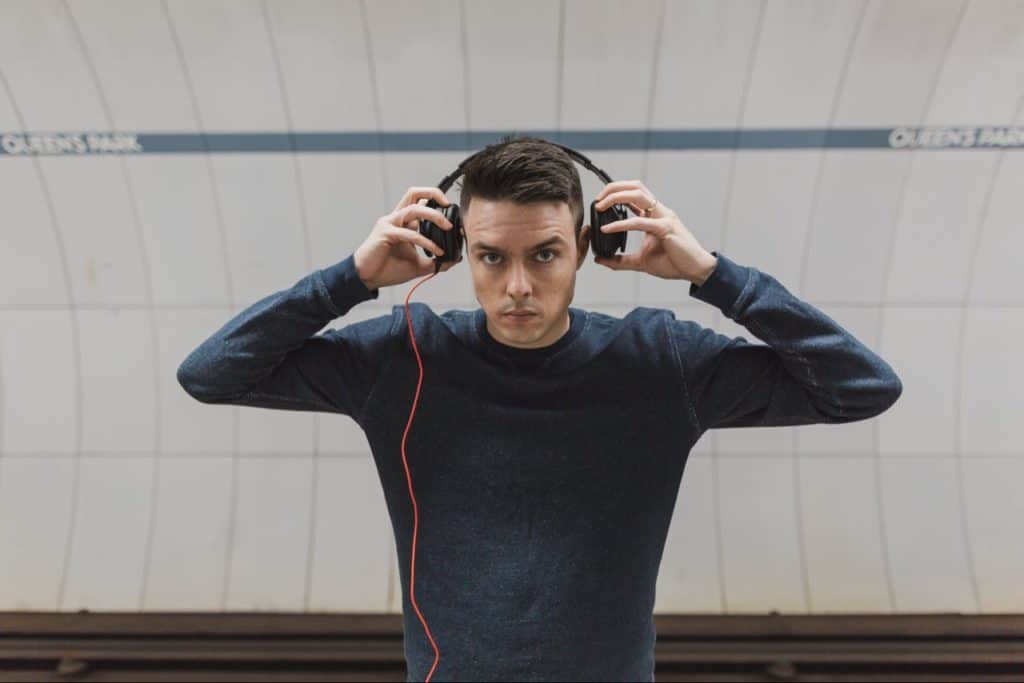 Young man putting on headphones with blue shirt.