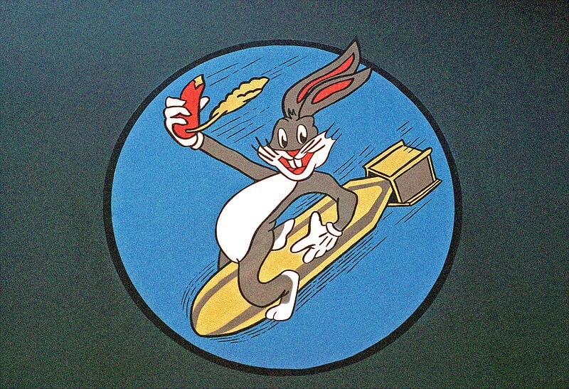 Bugs Bunny sitting and flying on a missile, with carrot in his hand.