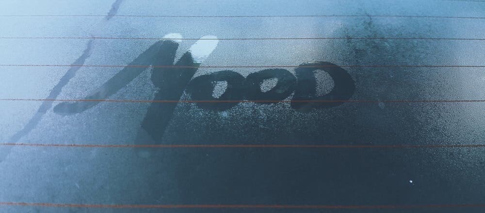 Mood word fingered out on windshield because of condensation.