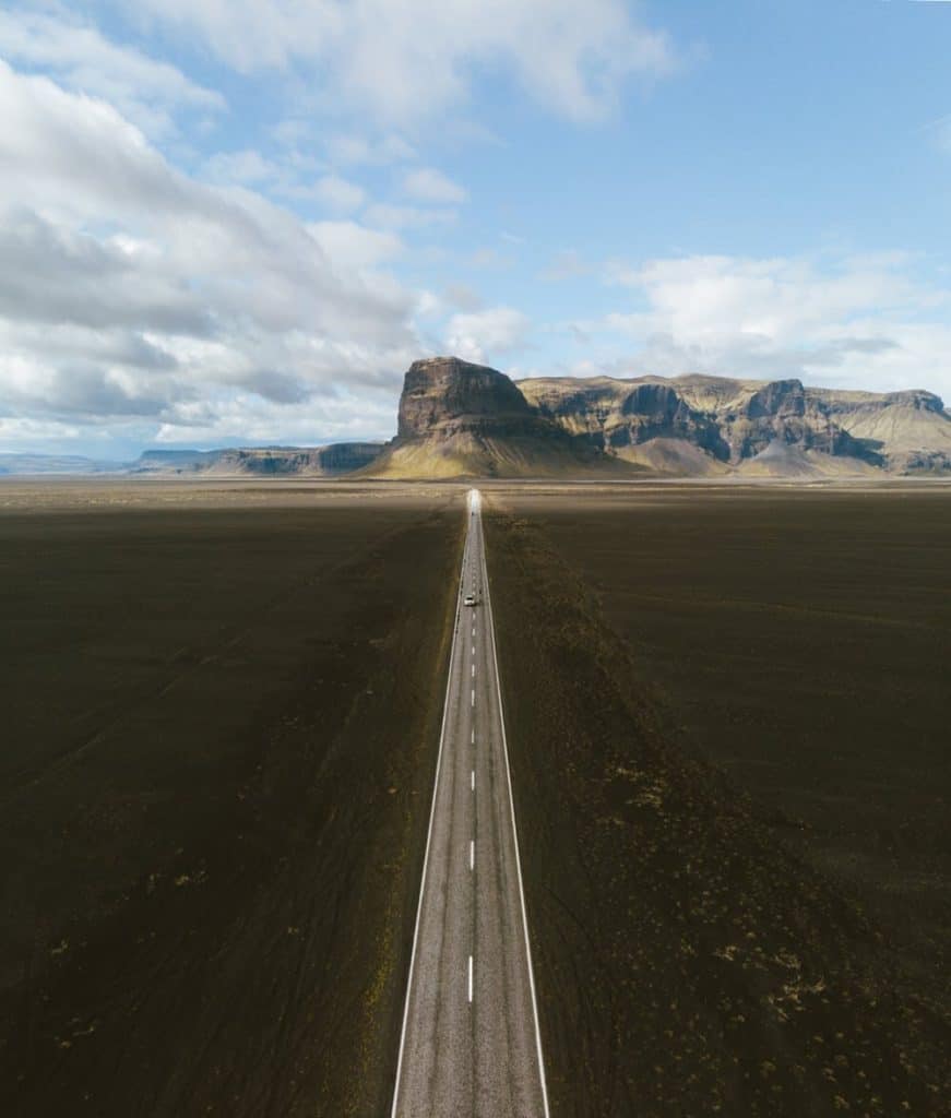 Long stretch of highway, outside of town, with mountains in back view. 