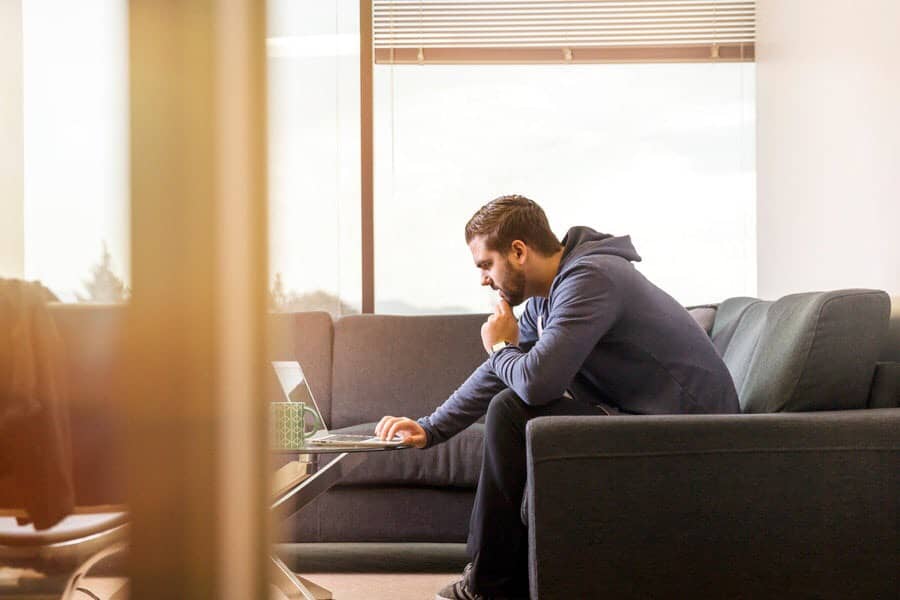 Person looking at laptop, from couch, in a room.