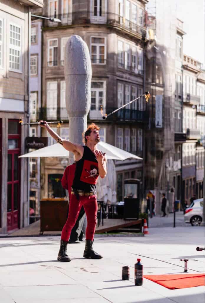 Man swinging bayonets with fire on them, fire on both sides of the bayonets. Swinging bayonets with both hands, outside in public.