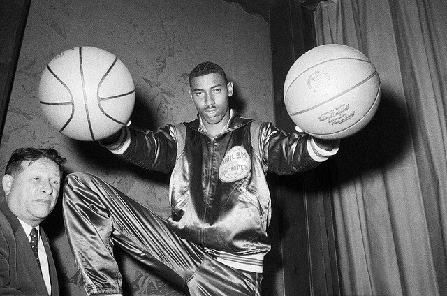 Original Caption: 6/18/1958-New York, NY- Wilt "The Stilt" Chamberlain, twice All-American at the University of Kansas, bedazzles Harlem Globetrotters' boss Abe Saperstein (R) with his basketball palming technique, after it was announced that Chamberlain had signed to play for the famous all-Negro team for a record high of $65,000 for one season. Chamberlain, who passed up his remaining year of eligibility at Kansas, becomes the draft choice of the pro Philadelphia Warriors next season. Photo courtesy of Tullio Saba/flickr.com