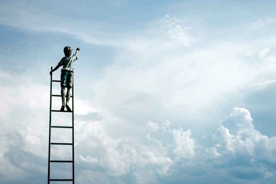 Kid on top of ladder, above the clouds, reaching toward the sky.