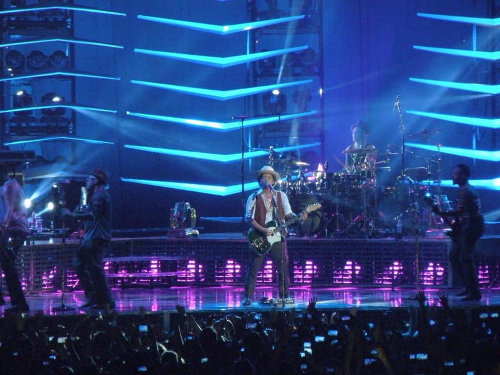 Bruno Mars playing guitar on stage with blue lights Image by Markéta Machová from Pixabay